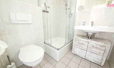 Modernes Bad mit Fenster, Dusche/WC und Handtuchtrocknerheizkörper.