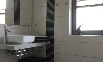 Das Badezimmer mit Waschplatz, großer  Echtglasdusche und WC