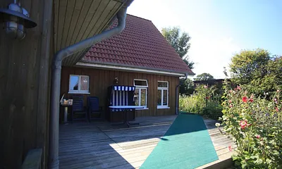 Holzterrasse mit Ostseeblick, Holzkohlegrill, Gartentisch mit 2 Gartenstühlen und einem Strandkorb.