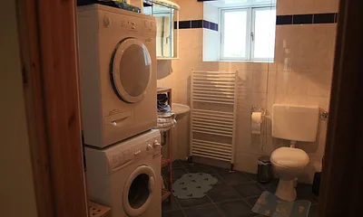 Badezimmer, linke Seite mit Waschbecken, Toilette, Waschmaschine und Wäschetrockner