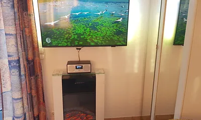 Großer 43 Zoll TV mit Ambilight LED-Hintergrundbeleuchtung an der Wand und Smart-TV Funktionen, Internetradio, elektrisches Kaminfeuer