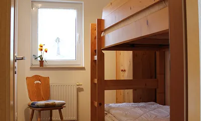 Im kleinen Zimmer steht ein stabiles Etagenbett mit verstellbaren Lattenrosten, separate Leselampen, eine Kommode