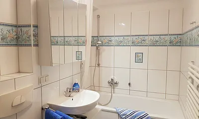 Maritimes Badezimmer mit Badewanne und Duscheinrichtung