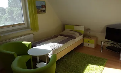 Schlafzimmer mit zwei Einzelbetten, TV und kleiner Stereoanlage im DG