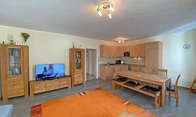 Wohnzimmer mit gemütlicher Eck- Couch mit Hocker, Couchtisch, Stehlampe, zwei Vitrinen, TV-Board mit Flachbild-TV sowie DVD-Player und CD-Player