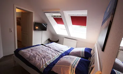 Schlafzimmer mit Doppelbett und Fernseher