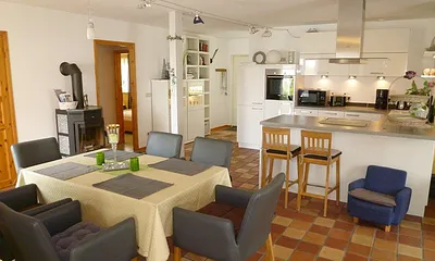 Esszimmer mit bequemen Lederstühlen mit Blick auf die offene, hochwertige und sehr moderne Küche