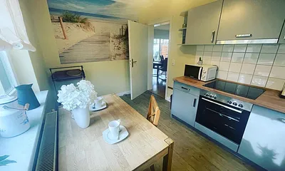 Eine vollausgestattete Küche mit Ceranfeld, Geschirrspüller, Kühlschrank mit Gefrierfach und vielen anderen Küchengeräten.