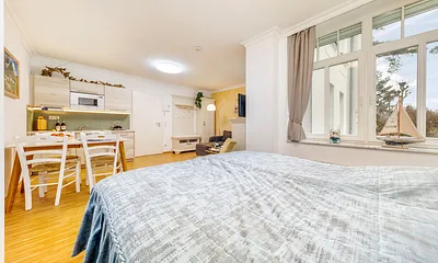 Das Fenster blickt Richtung Strandpromenade. Sie schauen auf die Düne, dahinter liegt das Meer.