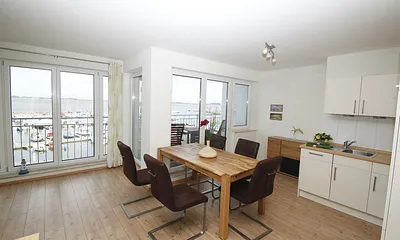 Koch-Essbereich mit Backofen und Geschirrspüler, daneben Balkon mit Panoramablick auf´s Wasser