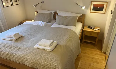 Schlafzimmer mit Naturholzbett und einer Ferderkernmatratze , TV zum abendlichen Abtauchen, direkter Zugang zum Badezimmer, Insektenschutz vor dem Fenster