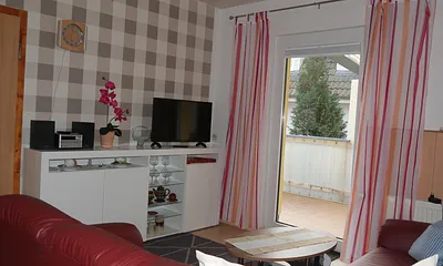 Wohnbereich mit TV, Couch und Blick auf die Terrasse.