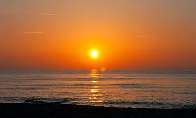 Im Hochsommer geht die Sonne vor dem Bakenberg im Meer unter