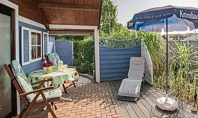 Sitzecke mit Sonnenschirm, Liege und Teich.