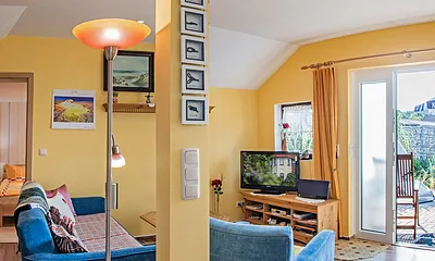 Wohnbereich mit Couch, TV und Blick auf die Terrasse.