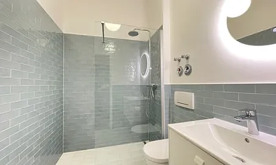 Das moderne Bad mit bodengleicher Dusche, WC und Waschtisch.