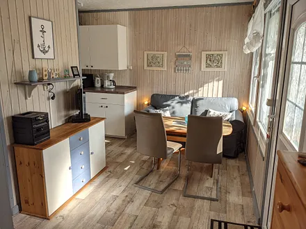 Wohnbereich mit Couch, Esstisch, offener Küche, Fernseher und DVD-Player