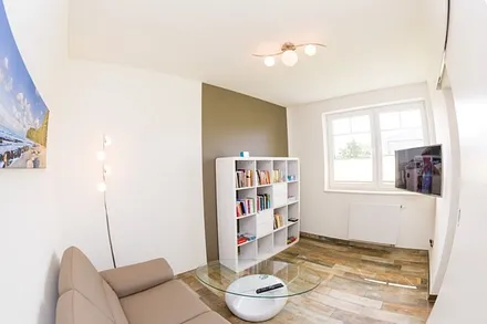 zweiter Wohnbereich mit Couch, TV und Auswahl an Büchern und Spielen