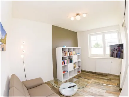 zweiter Wohnbereich mit Couch, TV und Auswahl an Büchern und Spielen