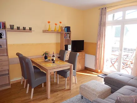 Wohnraum mit LCD-TV, Hifi-System, Sofa-Ecke, Esstisch, Küche u Blick zum Ostbalkon