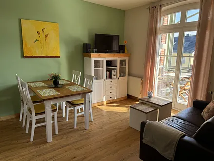 Wohnraum mit LCD-TV, Hifi-System, Sofa-Ecke, Esstisch, Küche u Blick zum Ostbalkon