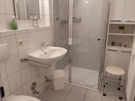 Geräumiges, weißes Duschbad mit Ablagemöglichkeiten, zahlreiche Haken für Handtücher und Duschhandtuchstange.usw. . 