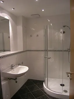 Hochwertig gestaltetes Bad mit Glas-Runddusche, Fußbodentemperierung und Panorama-Spiegel. 