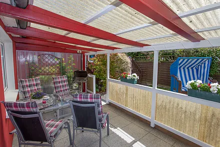 Umzäuntes Ferienhaus mit überdachter Terrasse.