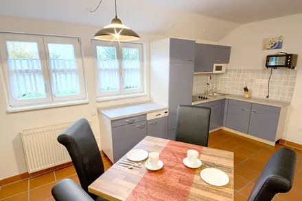 Komplett ausgestattete offene Einbauküche (Ceranfeld mit 4 Kochzonen, Grill- und Backautomat, Geschirrspüler, Toaster, Kaffeemaschine, Wasserkocher, Mikrowelle, Kühlschrank mit Gefrierfach, Geschirr).