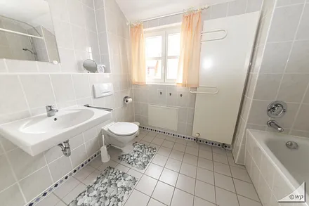 Modernes Bad mit Fenster, Badewanne/WC, Fön und Handtuchheizkörper.