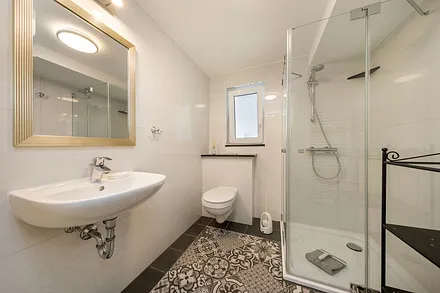 Das schicke Bad mit Echtglasdusche, Handtuchtrockner, Waschbecken, WC und Fenster.