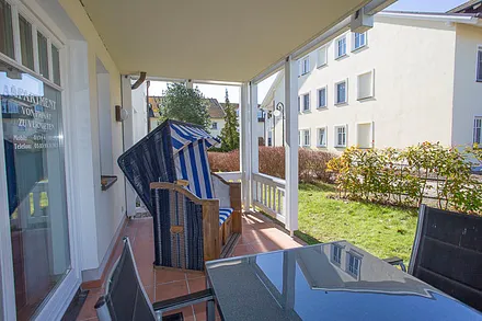 Geräumige Terrasse mit Süd-Westlage, großem Tisch, fünf Stühle und einem Strandkorb.