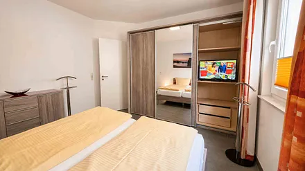 Schlafzimmer mit Doppelbett und zweitem Fernseher