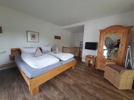 Schlafzimmer im ersten Obergeschoss mit Fernseher und Balkon