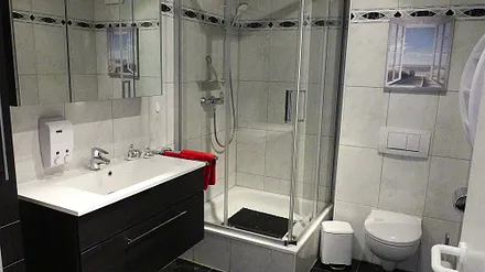 Duschbad mit Dusche (100x100), Toilette, Handtuchhalter, 3D Spiegel, Waschbecken, Schrank für mitgebrachte Gegenstände, Fön, Schminkspiegel, Hocker mit Schmutzwäschebehälter, Personenwaage