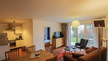 Wohnzimmer mit großem Esstisch, offener Küche und Blick auf Terrasse und Garten, Sofa, Kommode, TV