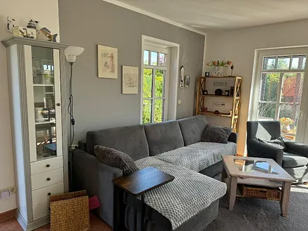 Wohnecke mit Schlafcouch und Durchgang zum Wintergarten