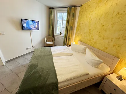 Schlafzimmer mit Doppelbett (1,60 m x 2,00 m), kleiner Flachbildschirm, Nachttischkonsolen, begehbarem Kleiderschrank und Insektenschutzgitter