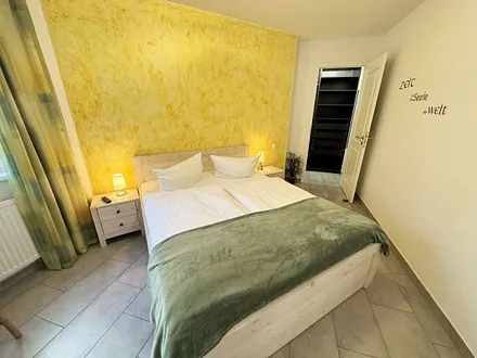 Schlafzimmer mit Doppelbett (1,60 m x 2,00 m), kleiner Flachbildschirm, Nachttischkonsolen, begehbarem Kleiderschrank und Insektenschutzgitter