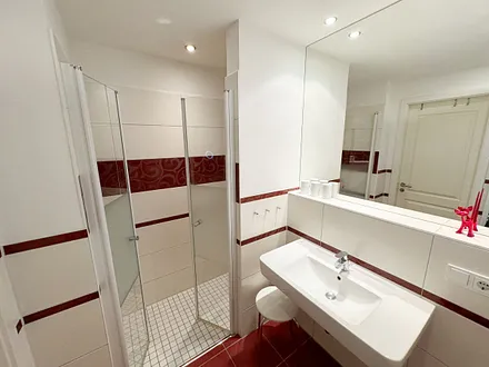 Badezimmer mit ebenerdiger Dusche, Waschbecken, WC, Fön, Kosmetikspiegel und Handtuchheizkörper