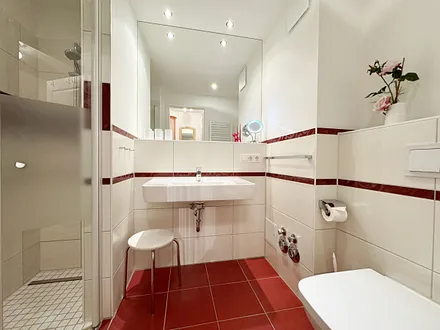 Badezimmer mit ebenerdiger Dusche, Waschbecken, WC, Fön, Kosmetikspiegel und Handtuchheizkörper