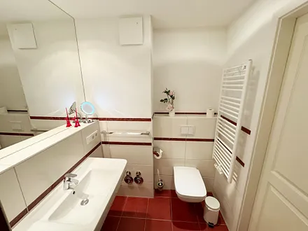 Badezimmer mit ebenerdiger Dusche, Waschbecken, WC, Fön, Kosmetikspiegel und Handtuchheizkörper