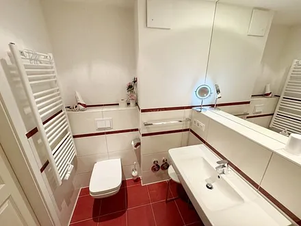 Badezimmer mit ebenerdiger Dusche, Waschbecken, WC, Fön, Kosmetikspiegel und Handtuchheizkörper