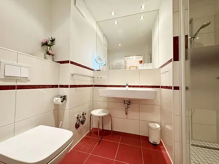 Badezimmer mit ebenerdiger Dusche, Waschbecken, WC, Fön, Kosmetikspiegel und Handtuchheizkörper