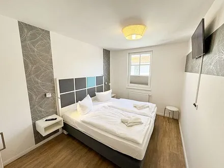 Schlafzimmer mit Boxspringbett (1,80 m x 2,00 m), Nachttischkonsolen, Kleiderschrank und LED-TV