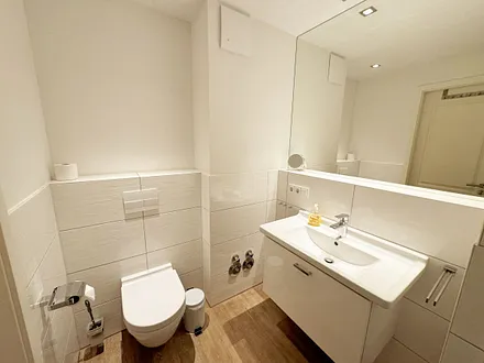 Badezimmer mit ebenerdiger Dusche, Waschbecken, WC und Handtuchheizkörper