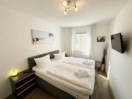 Schlafzimmer mit komfortablen Boxspringbett (1,80 m x 2,00 m), hochwertige durchgehende Matratze, Nachttischkonsolen, 2-trg. Kleiderschrank und TV