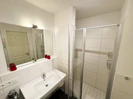 Badezimmer mit ebenerdiger Glasdusche, Fön, Waschbecken, WC und Handtuchtrockner