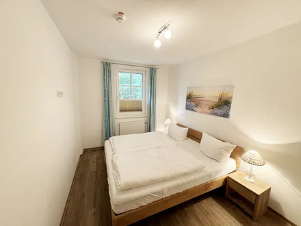 Schlafzimmer mit Doppelbett (1,80 m x 2,00 m), Nachttischkonsolen, Kleiderschrank, Fliegenschutzgitter und Verdunklungsplissees 