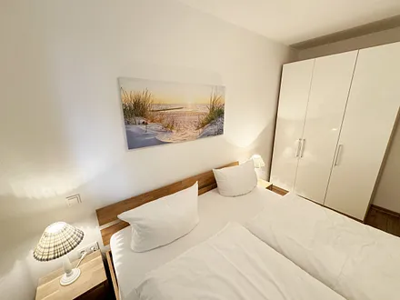 Schlafzimmer mit Doppelbett (1,80 m x 2,00 m), Nachttischkonsolen, Kleiderschrank, Fliegenschutzgitter und Verdunklungsplissees 